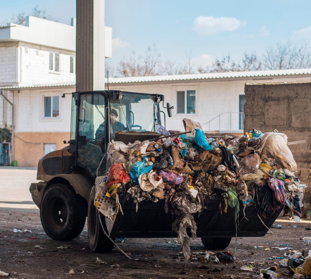 An excavator carries a heap of garbage at waste sorting plant